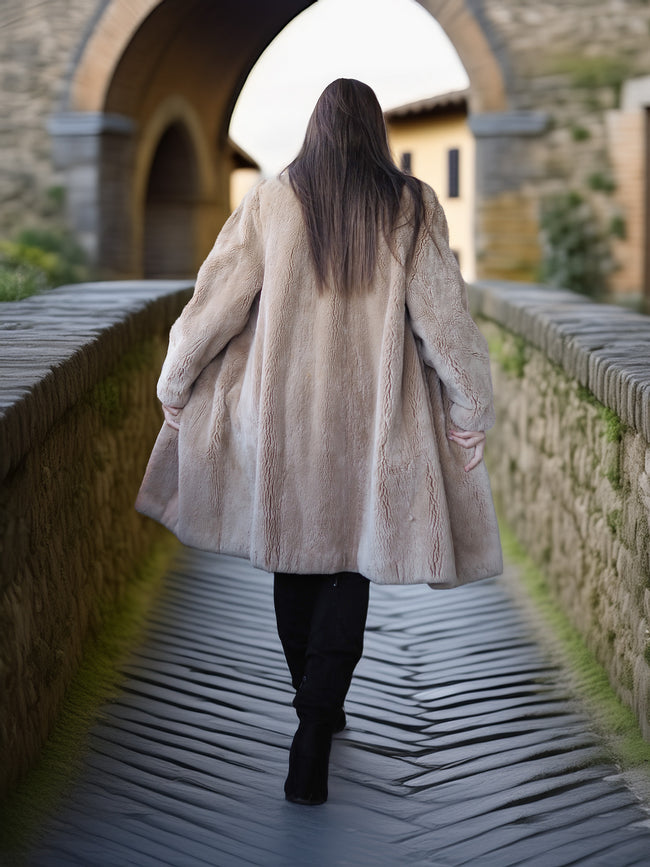 Person wearing a long coat walking on a stone bridge with a stone building in the background