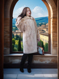 Woman in a fur coat standing in front of an archway with a scenic view.
