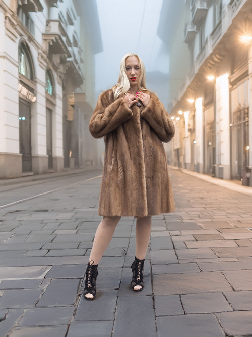 Model stands confidently in classic pastel brown mink fur coat stroller jacket M/L. Timeless and luxurious fur fashion for women.