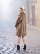 Model walks away in classic pastel brown mink fur coat stroller jacket M/L on cobblestone street. Elegant and timeless mink fashion.
