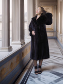 Woman in a black fur coat standing in an elegant interior setting with columns and marble floor.