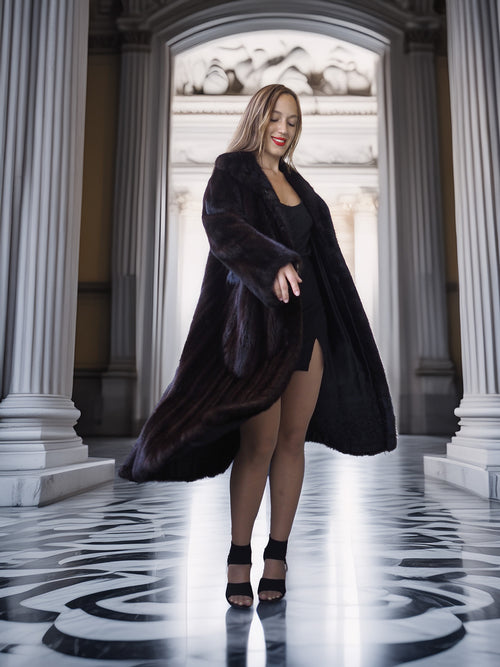 Woman in a long black coat standing in a classical architectural setting
