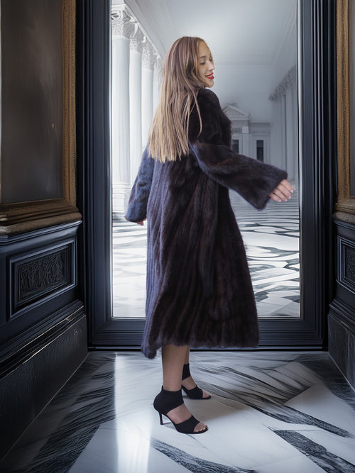 Woman in a fur coat standing in front of a large mirror in an elegant interior setting.