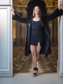 Woman in a black coat standing in an elegant interior setting