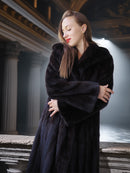 Woman wearing a dark fur coat in an indoor setting with architectural columns.
