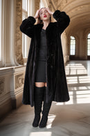 Woman wearing a long black coat in an elegant interior setting
