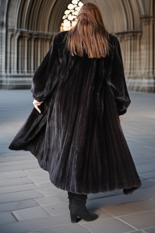 Person wearing a long black fur coat walking away from a cathedral entrance.