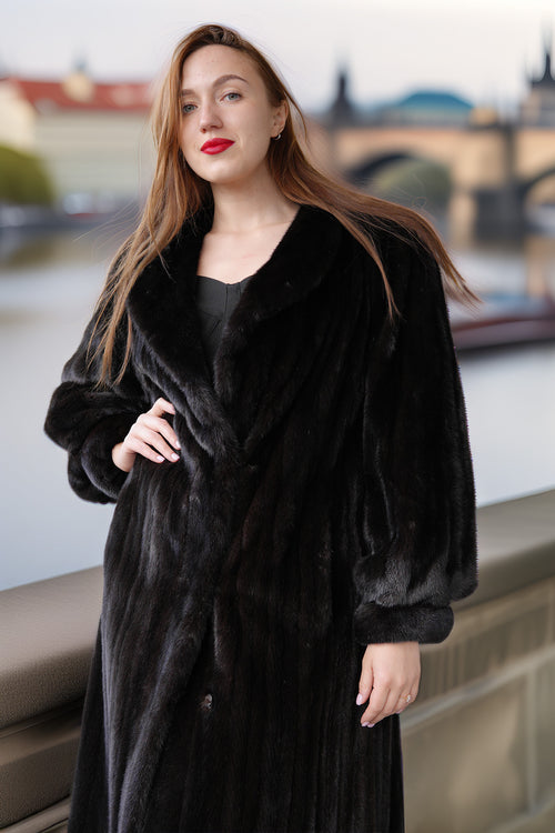 Woman wearing a black fur coat with a blurred cityscape background
