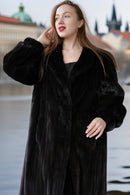 Woman wearing a black fur coat with a blurred cityscape background