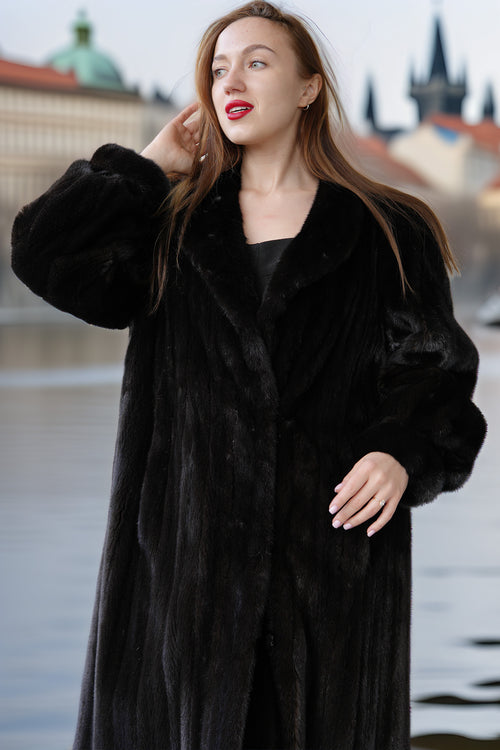 Woman wearing a black fur coat with a blurred cityscape background