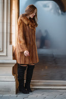 Caramel-brown mink fur coat with wide fur collar and straight hem over black boots