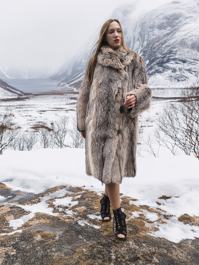 Model in fur coat walking through snowy landscape