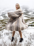 Model twirling in plush fur coat in snowy setting