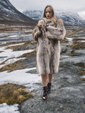 Model in fur coat walking on snowy rocky terrain