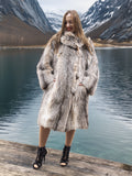 Model smiling in plush fur coat by a lake