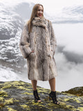 Model in fur coat on mossy rock with misty backdrop