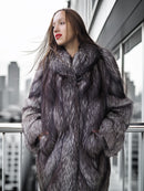 Woman wearing a fur coat standing on a balcony with cityscape background