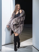 Woman wearing a fur coat and black boots in a doorway.