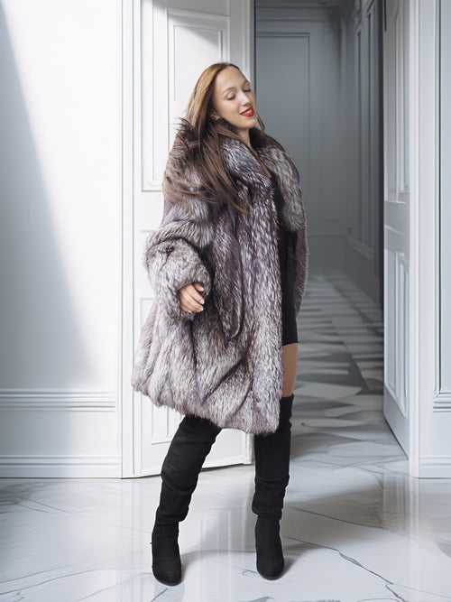 Woman wearing a fur coat in a hallway with white walls and marble floor.
