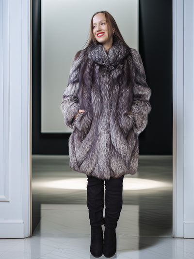 Woman wearing a fur coat standing in a doorway.