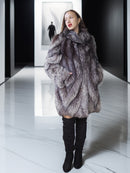 Woman wearing a fur coat on a reflective floor with a blurred background