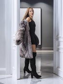 Woman wearing a fur coat and black outfit in a stylish interior setting