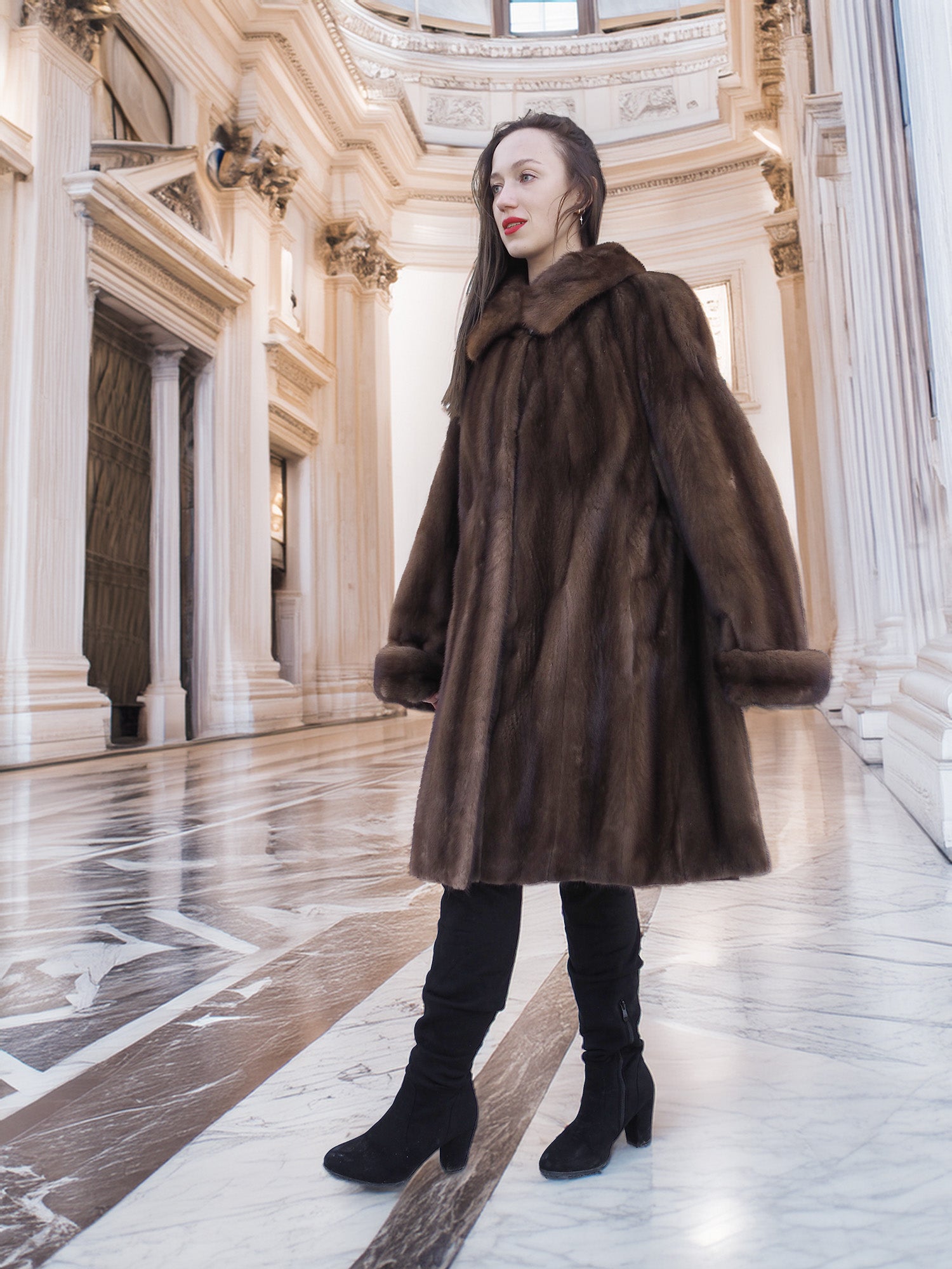 Side view of Brand New Luxurious Demi Buff Swing Canadian Mink Fur Coat L/XL, styled with black boots in a grand marble interior.