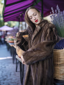 Woman wearing a fur coat holding a basket outdoors with a blurred background