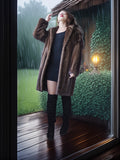 Person wearing a brown fur coat and black boots standing on a wooden deck with a rainy background.