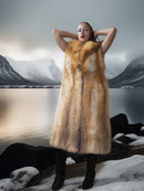 Person wearing a fur vest in a snowy landscape with mountains.