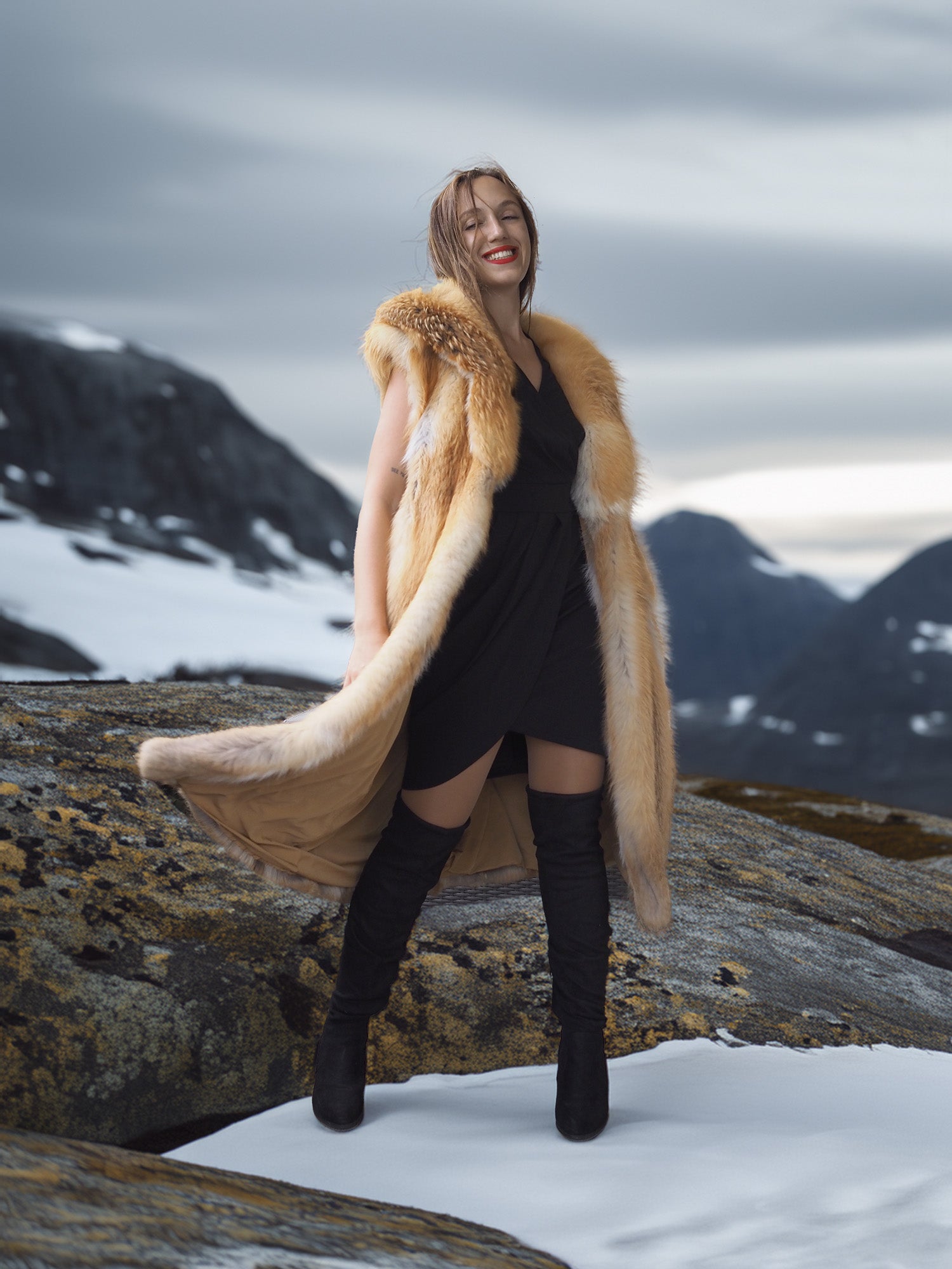Woman in a fur coat standing on a snowy mountain landscape