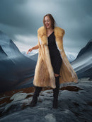 Woman in a fur coat standing on a mountain with a scenic background