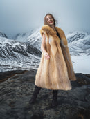 Person wearing a fur coat standing in a snowy mountain landscape