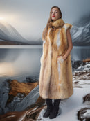 Person wearing a fur coat standing in a snowy landscape with mountains in the background