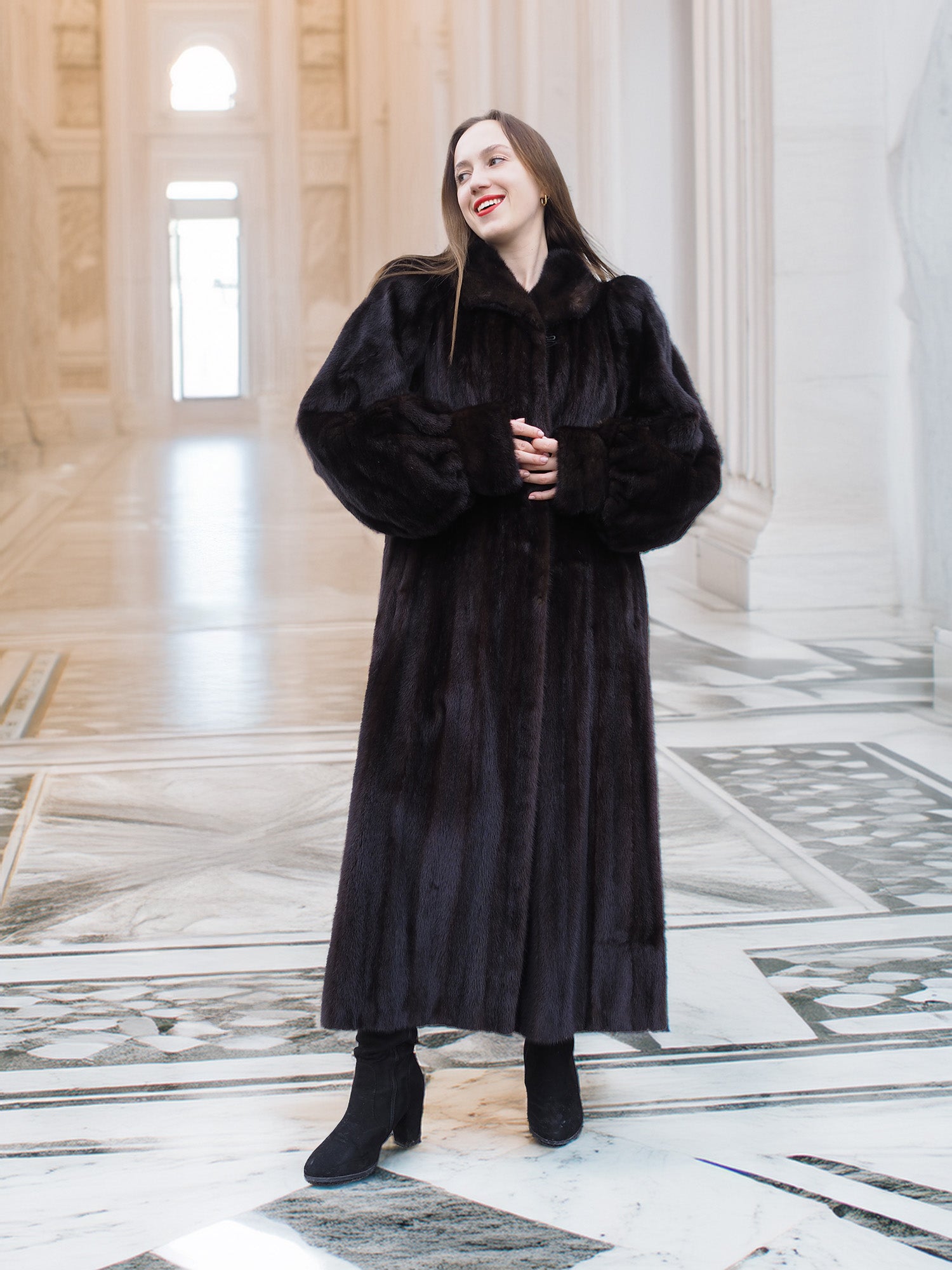 Elegant black mink fur coat styled in a marble corridor, combining warmth and sophistication for premium cold-weather outerwear.