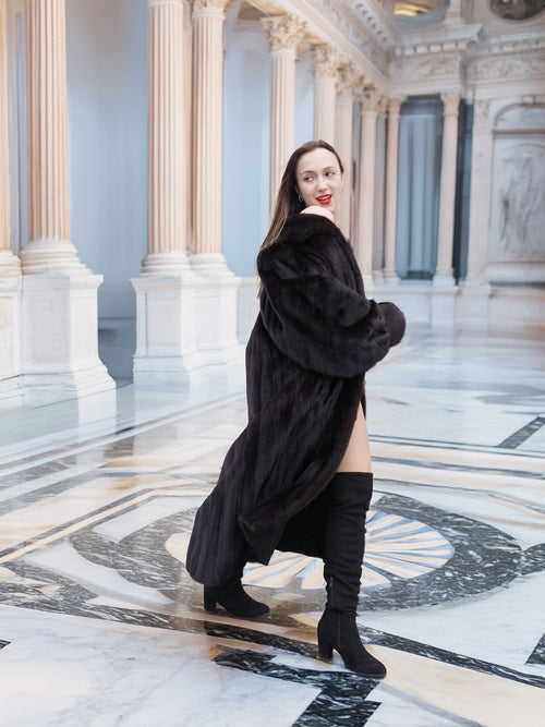 Model turns in black mink coat in marble hall, showcasing luxurious fur movement and timeless cold-weather elegance.