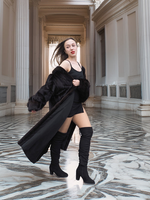 Model reveals black mini outfit under flowing mink coat, blending bold fashion with the warmth of real fur outerwear.