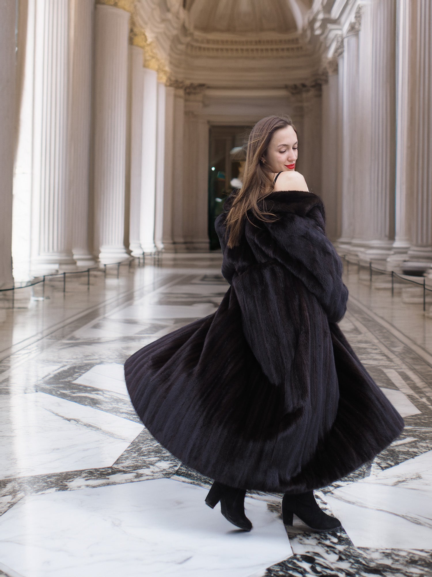 Model twirls in full-length black mink coat, revealing its voluminous design and luxurious movement for winter elegance.