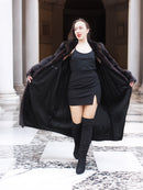 Model opens black mink coat to reveal black mini dress, combining bold fashion with luxury fur outerwear appeal.