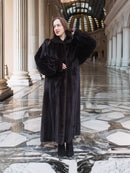 Full-length black mink fur coat styled with boots in a grand architectural setting, perfect for luxury cold-weather fashion.