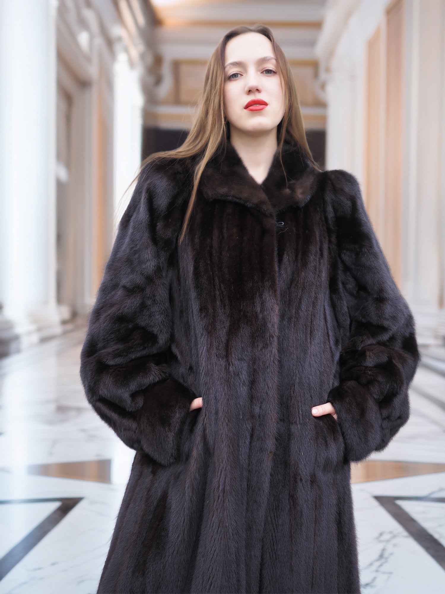 Close-up of model in black mink coat with hands in pockets, highlighting rich fur texture and elegant winter style.