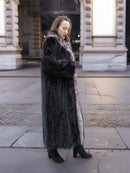 Side profile of black mink coat with indigo fox trim, styled for a sleek and warm winter look in L/XL sizing.
