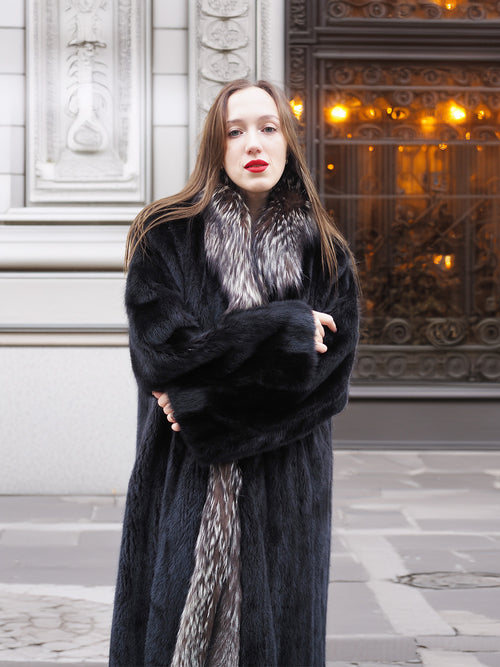 Front view of black mink coat with silver fox collar, arms crossed to highlight warmth and plush fur texture.