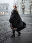 Turning pose in black mink coat with silver fox collar, showcasing luxurious volume and elegant winter styling.