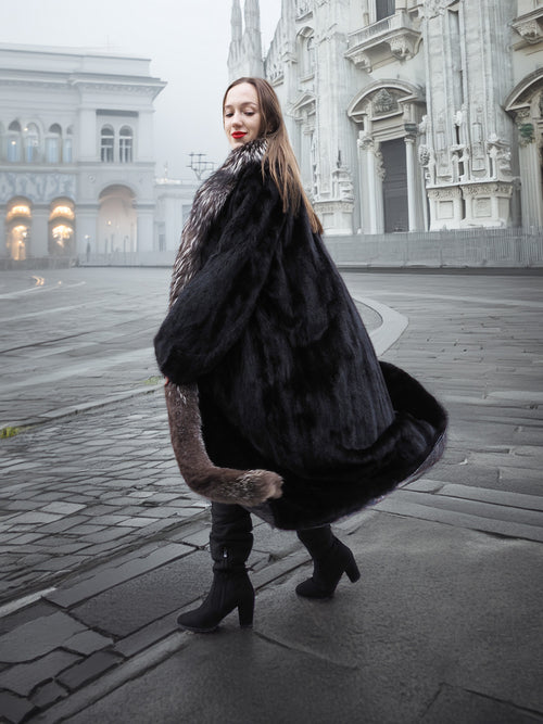 Turning pose in black mink coat with silver fox collar, showcasing luxurious volume and elegant winter styling.