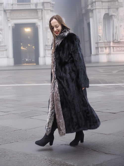Walking pose in black mink coat with indigo fox collar, showcasing movement and luxurious fur texture for winter fashion.