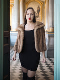 Woman wearing a fur coat and black dress in an elegant interior setting