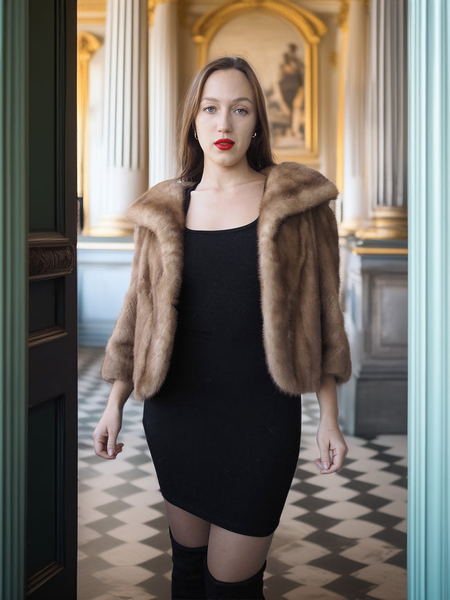 Woman wearing a fur coat and black dress in an elegant interior setting