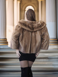 Person wearing a fur coat standing on steps with classical architecture in the background