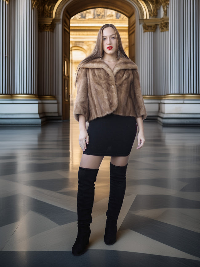 Woman in a fur coat and black knee-high boots standing in an ornate hall.